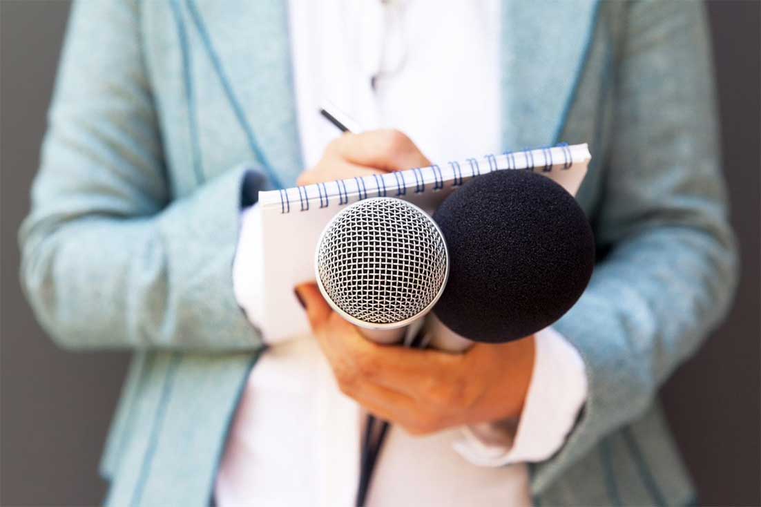 Journalist writing notes and holding microphones